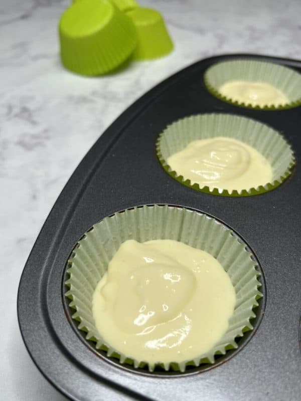 mini apple cheesecake filling on top of grraham cracker crumbs in cupcake liners