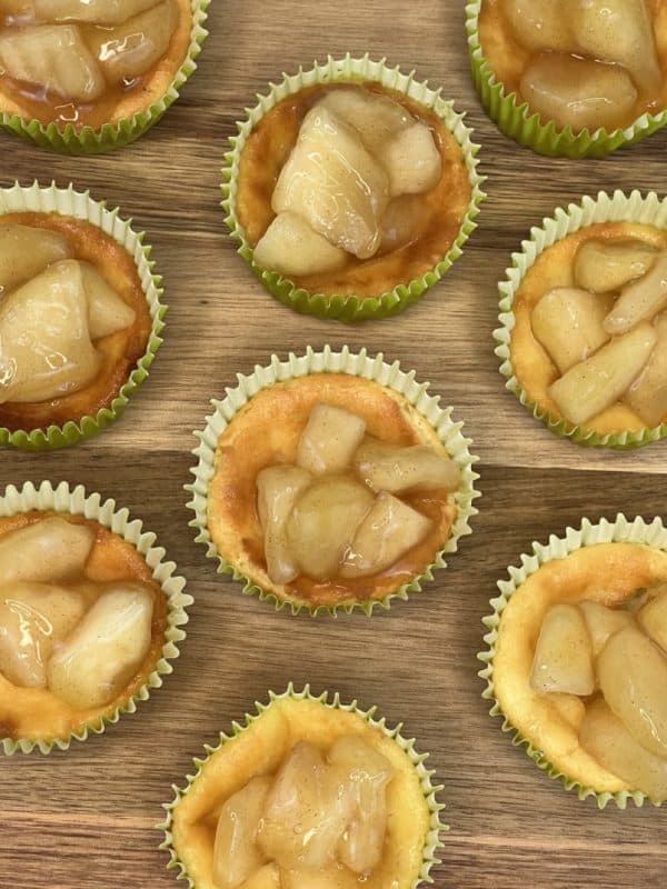 array of mini apple cheesecakes on a wooden surface