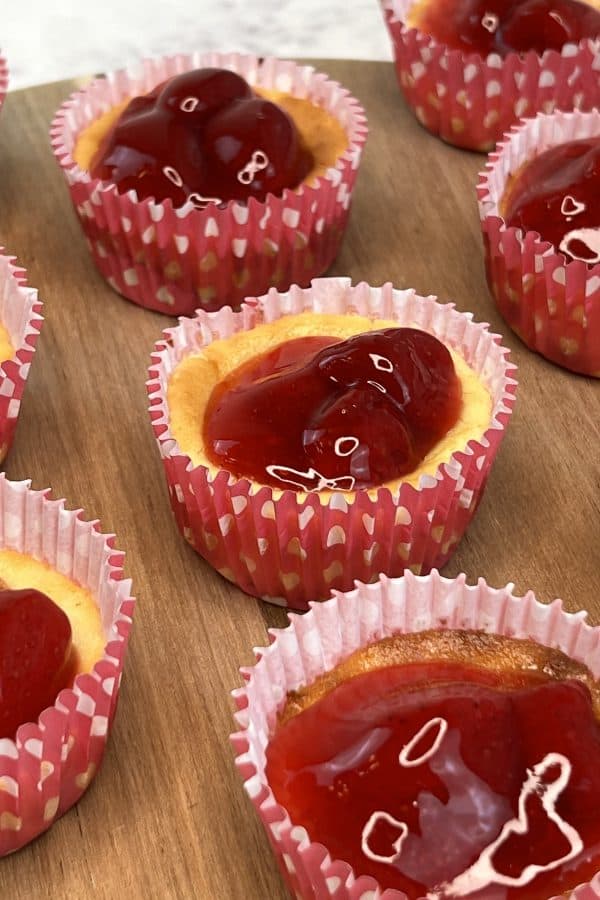mini strawberry cheesecake tarts on a wooden board