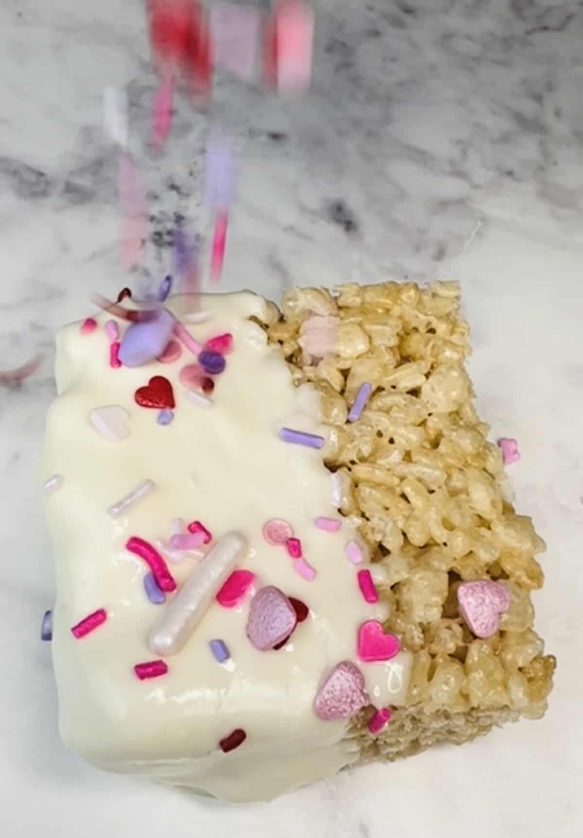 valentine sprinkles landing on valentine rice krispie treat melted white chocolate