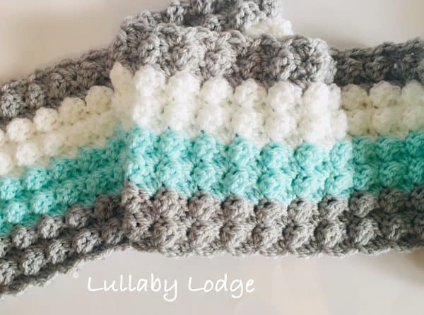 Blanket in the making process in gray, white, and green colors