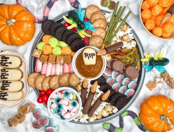 pop sugar-halloween dessert board with cookies, candies, and more including a caramel dip.