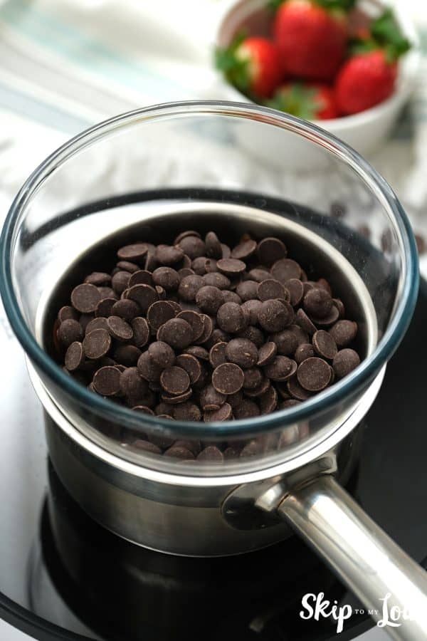 Glass bowl with chocolate chips sitting on top of a silver pan, by Skip to my Lou.