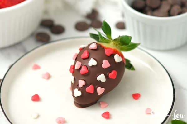 One chocolate covered strawberry with stem and leaves with red, white and pink candy hearts on top by Skip to my Lou.