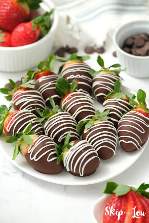 12 chocolate covered strawberries with stems with white chocolate zig-zagged across each berry, by Skip to my Lou.