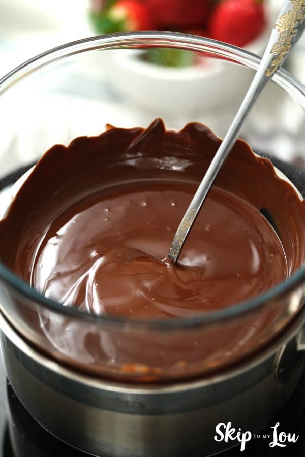 Silver spoon sticking out of melted chocolate in a glass bowl, by Skip to my Lou.