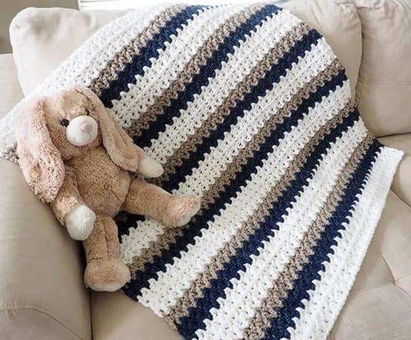 Baby blanket in white gray and brown with a rabbit plushie.