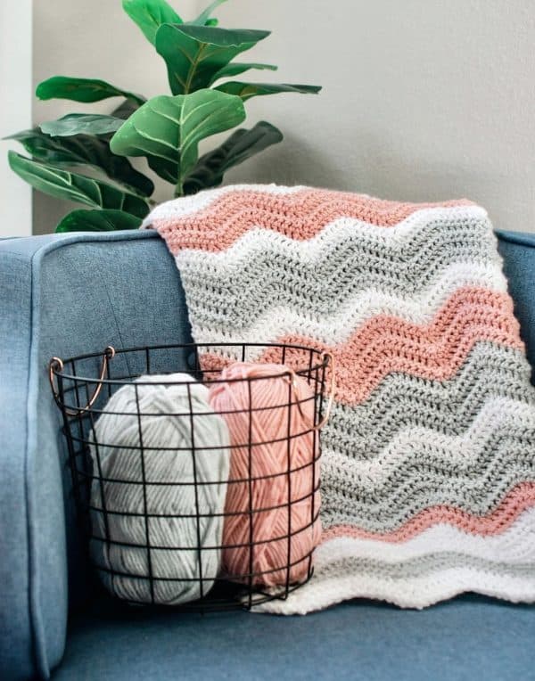 Pink white and gray blanket with yarn next to it