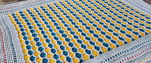 Crochet blanket in yellow white and blue colors.