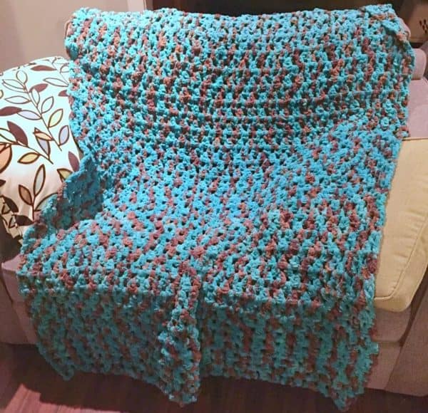 Blue and gray blanket displayed on top of a sofa.