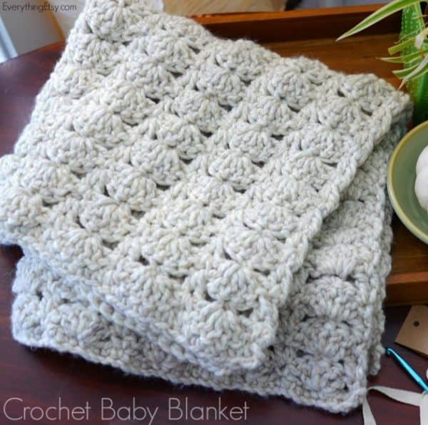 White yarn blanket for baby folded in a chair.