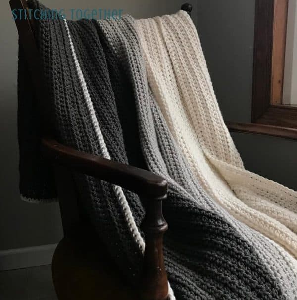 Large white and gray blanket hanging from a chair.