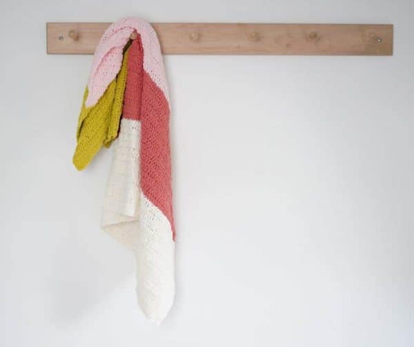 White pink and salmon blanket hanging from a wall