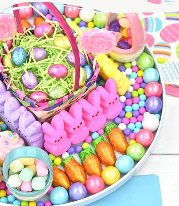 A edible Easter basket in the middle surrounded by pastel and bright Easter candies, some in small ceramic baskets from bullock's buzz.