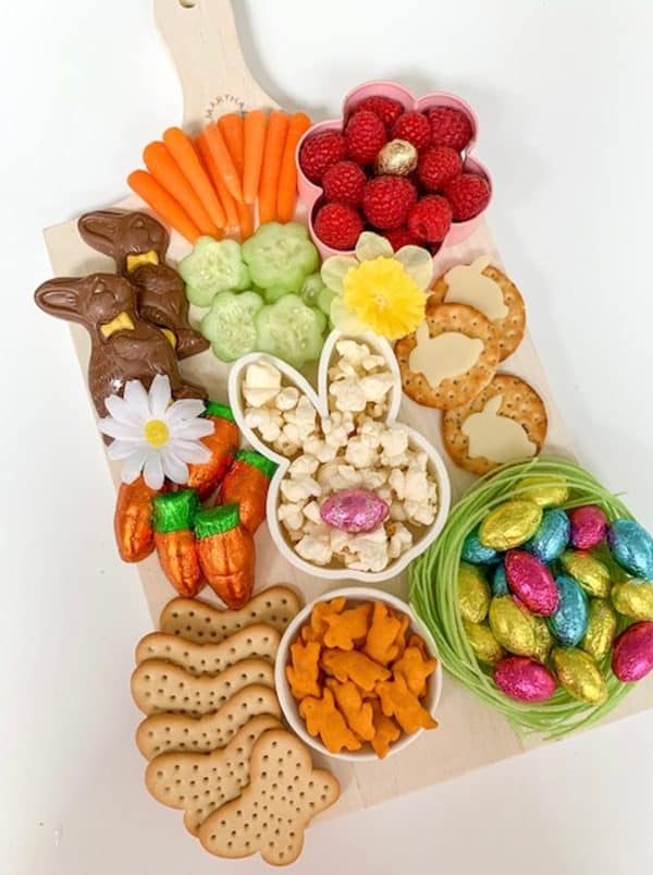 A simple charcuterie board for a couple people, including traditional aspects like cheese, veggies, fruit, and some candy from Party Pinching
