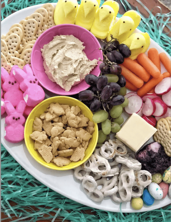 Easter charcuterie board ideas from coffee pancakes and dreams with a variety of candies, crankers, and a hummus dip.