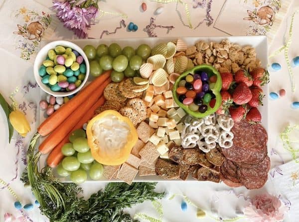 Easter charcuterie board ideas from Detroit mom that includes kid friendly snacks like veggie chips, chocolate covered pretzels, and bell pepper bowls filled with dips and jelly beans.