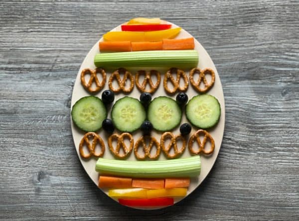 Easter charcuterie board ideas from DIY gifts that is simple enough to eat in one sitting with blueberries, cucumbers, peppers and more in the design of an Easter egg.