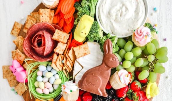 Easter charcuterie board ideas from Healthy Little Peach includes a chocolate bunny, robin eggs, spring cupcakes, and some more traditional charcuterie foods like grapes, crackers, and dip.