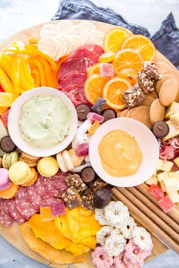 A bright colored Easter charcuterie board from Lemons for lulu with avocado and lemon curb dips.