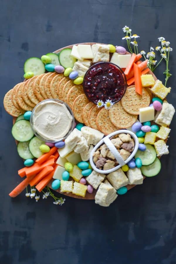 Easter charcuterie board ideas-mozielife- a pastel colored board with jam for dipping and a basket of chocolate and vanilla Easter bunny cookies.