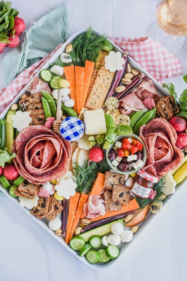 Easter charcuterie board ideas-mymoderncookery-a charcuterie board with salami roses, different jellies, flower and carrot-shaped cheese.