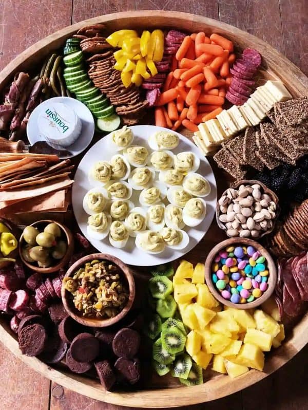 Easter charcuterie board from reluctant entertainer with deviled eggs in the center and a variety of foods surrounding them.
