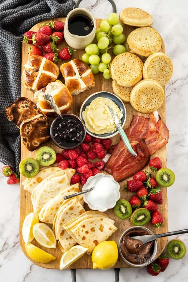 Easter charcuterie board ideas from sugar salt magic that includes some brunch options like bacon, biscuits, hot cross buns and more.