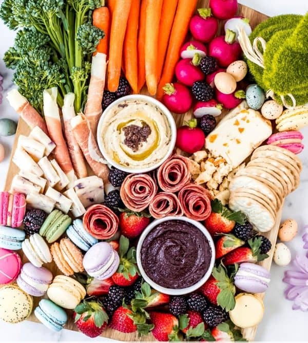 Easter charcuterie board ideas from Wanderlust & Wellness that includes macroons, crackers, chocolate dip, fresh veggies and fruit.