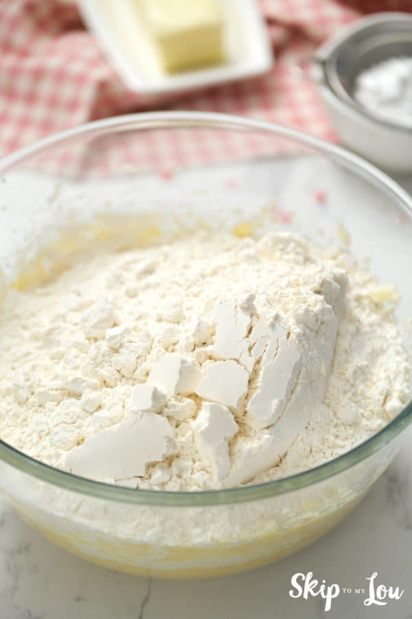 Glass mixing bowl with sugar and butter mixture on the bottom and flour on top, by Skip to my Lou.