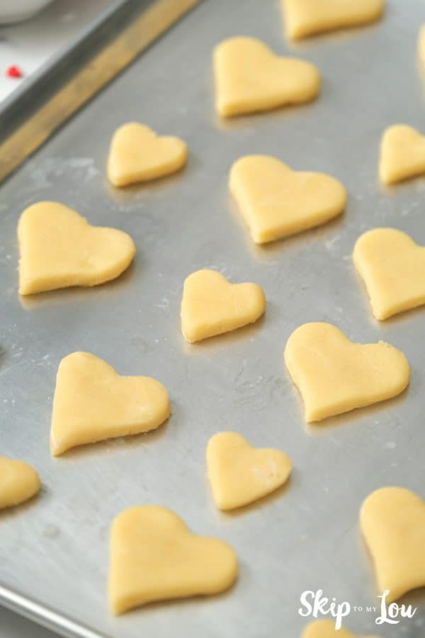 12 heart-shaped sugar cookies on a cookie sheet after baking, by Skip to my Lou.