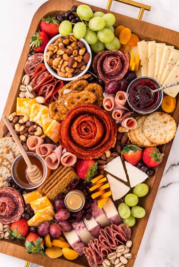 A charcuterie try with crackers, salami roses, cheese slices, and dips from Easy Appetizers