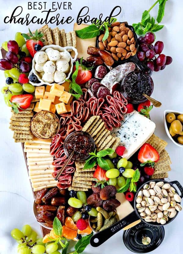 A large charcuterie board with unique options like mozzarella balls, spicy mustard, two types of jams, dried figs, and more from