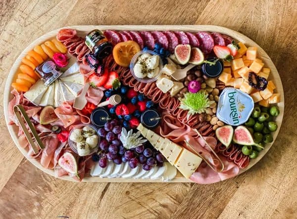 A non-traditional charcuterie board with an array of meats, cheese cubes, and other options.