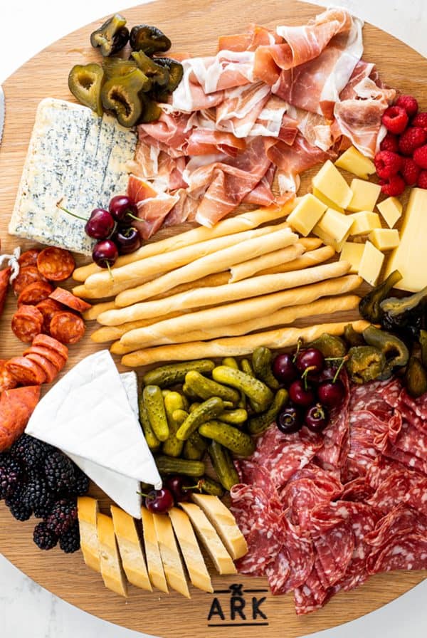 A simple meat charcuterie board from Simply Delicious with blue cheese, breadsticks, and three types of meat.