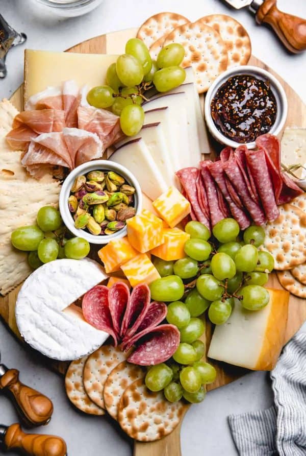 A simple charcuterie board with cheese slices, crackers, meat, grapes, and jam from Veronika's Kitchen