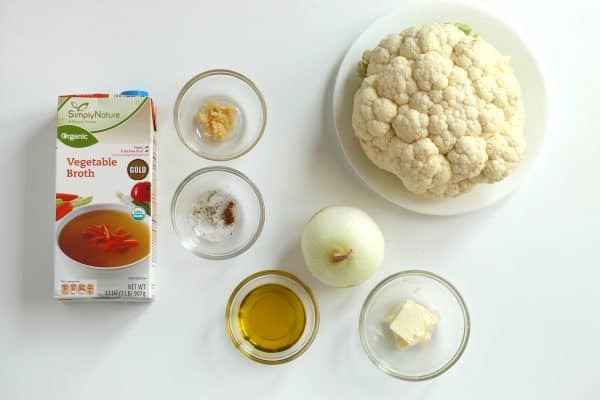 Ingredients for cauliflower soup: vegetable broth, minced garlic, salt, nutmeg, pepper, a white onion, olive oil, butter and a head of cauliflower, by Skip to my Lou.