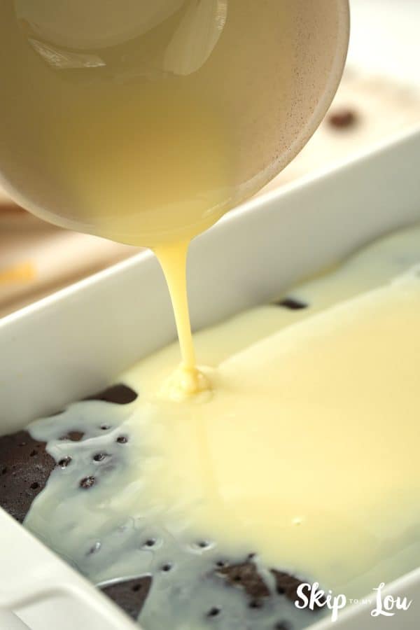 Chocolate cake baked in a rectangle-shaped pan with sweetened condensed milk poured over the top, by Skip to my Lou.