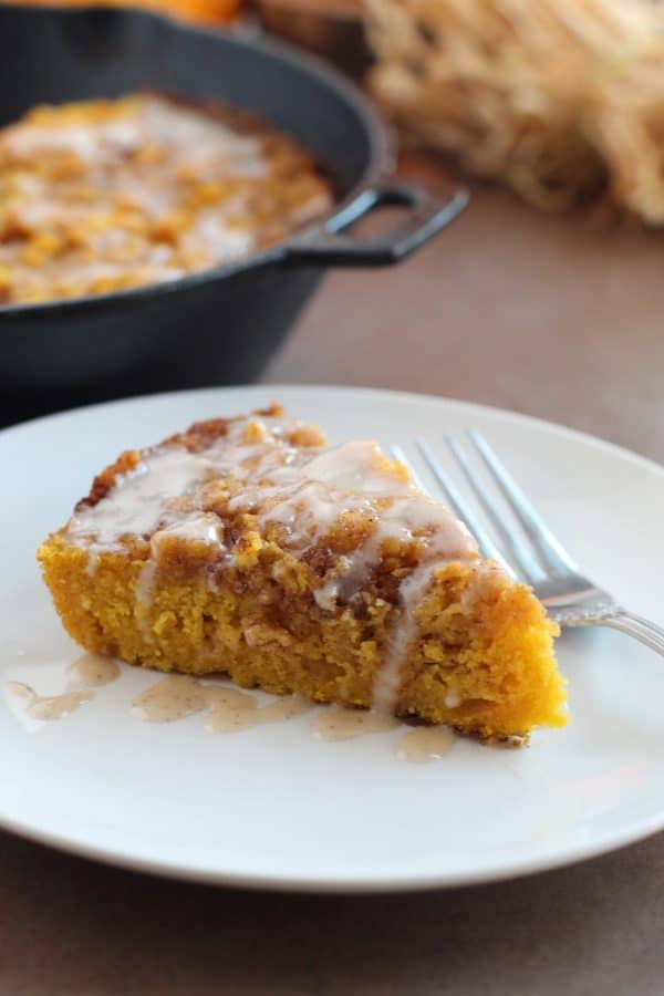 Slice of pumpkin cinnamon roll skillet cake served on a white plate with a silver fork, by Skip to my Lou.