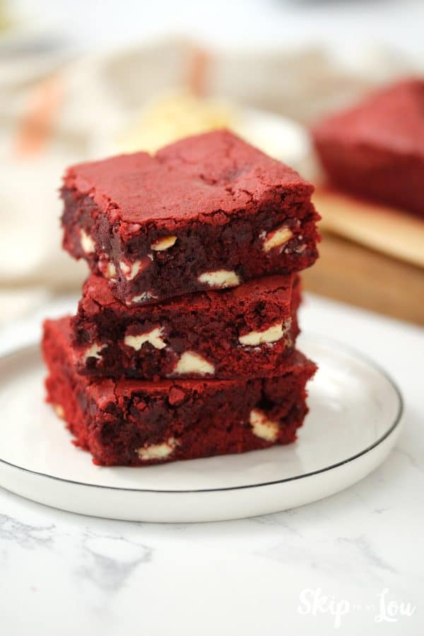 Three Red Velvet brownies stacked up on a white plate, by Skip to my Lou