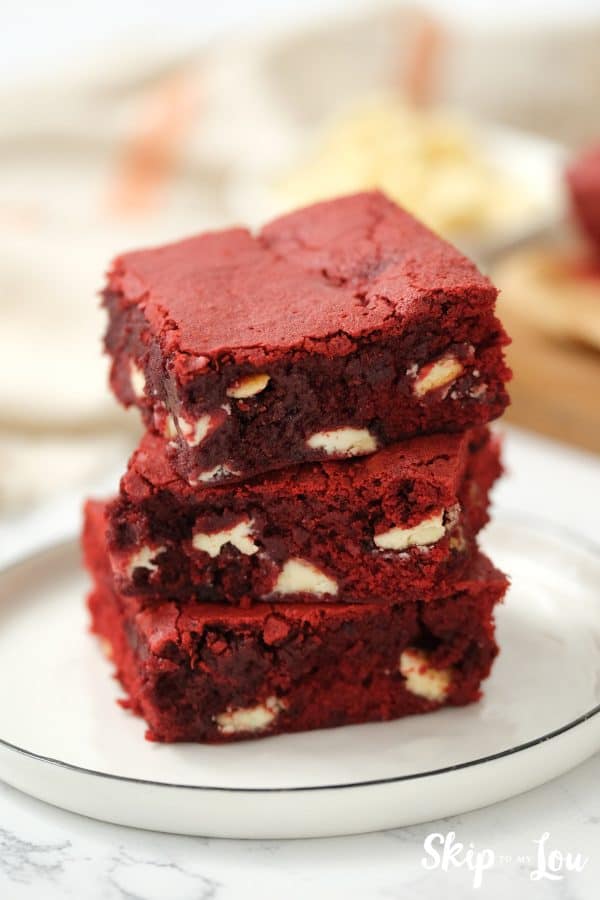 Three square red velvet brownies sitting on top of each other in a stack, by Skip to my Lou.