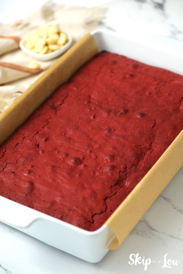 White ceramic baking dish lined with parchment paper and a Red Velvet brownie baked inside, by Skip to my Lou.