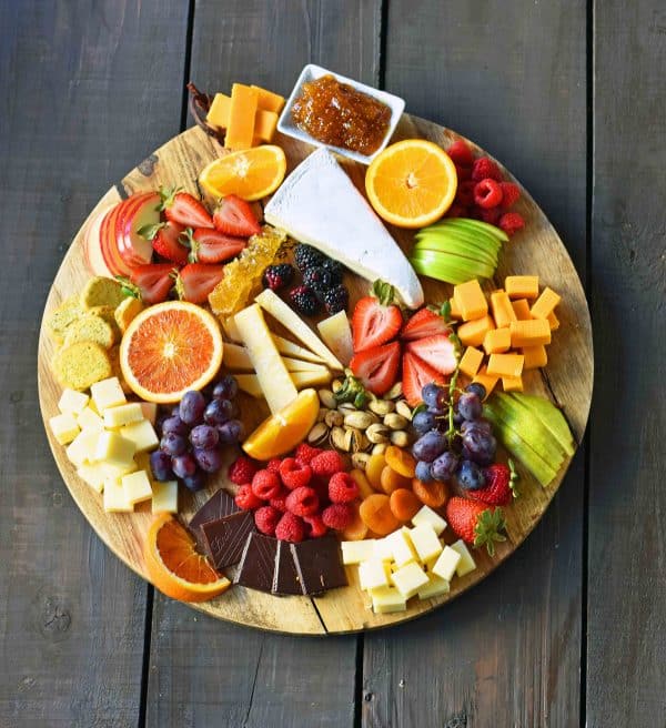 modern honey has a simple board with a variety of fruit, cheese, and a fruit dip.