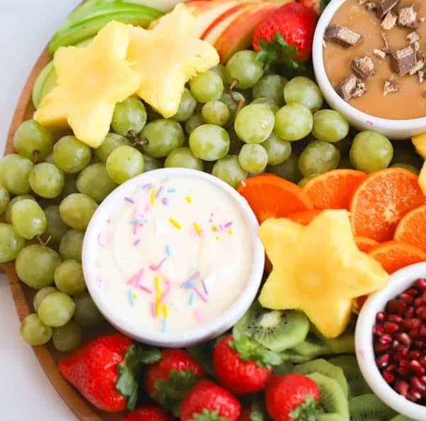 the carefree kitchen has a homemade fruit dip with grapes, pineapples, and oranges around it,