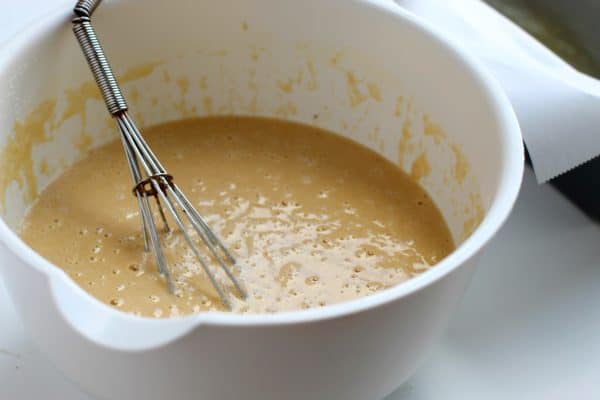 Whisk inside of a white mixing bowl holding whisked batter for paleo bread, by Skip to my Lou.