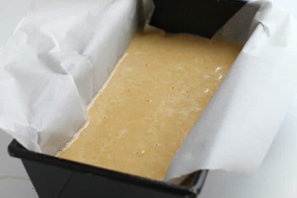 Paleo bread batter inside black loaf pan lined with parchment paper for easy removal from pan after baking, by Skip to my Lou.