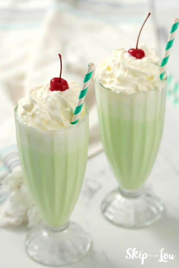 two tall glasses of shamrock shake with whipped cream and cherry on top from Skip to my Lou recipe