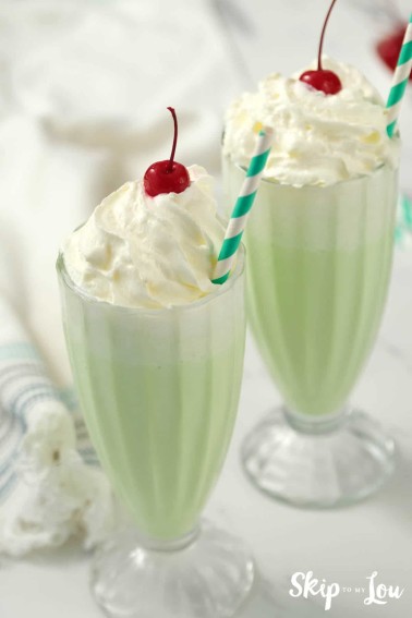 two tall glasses of shamrock shake with whipped cream and cherry on top from Skip to my Lou recipe