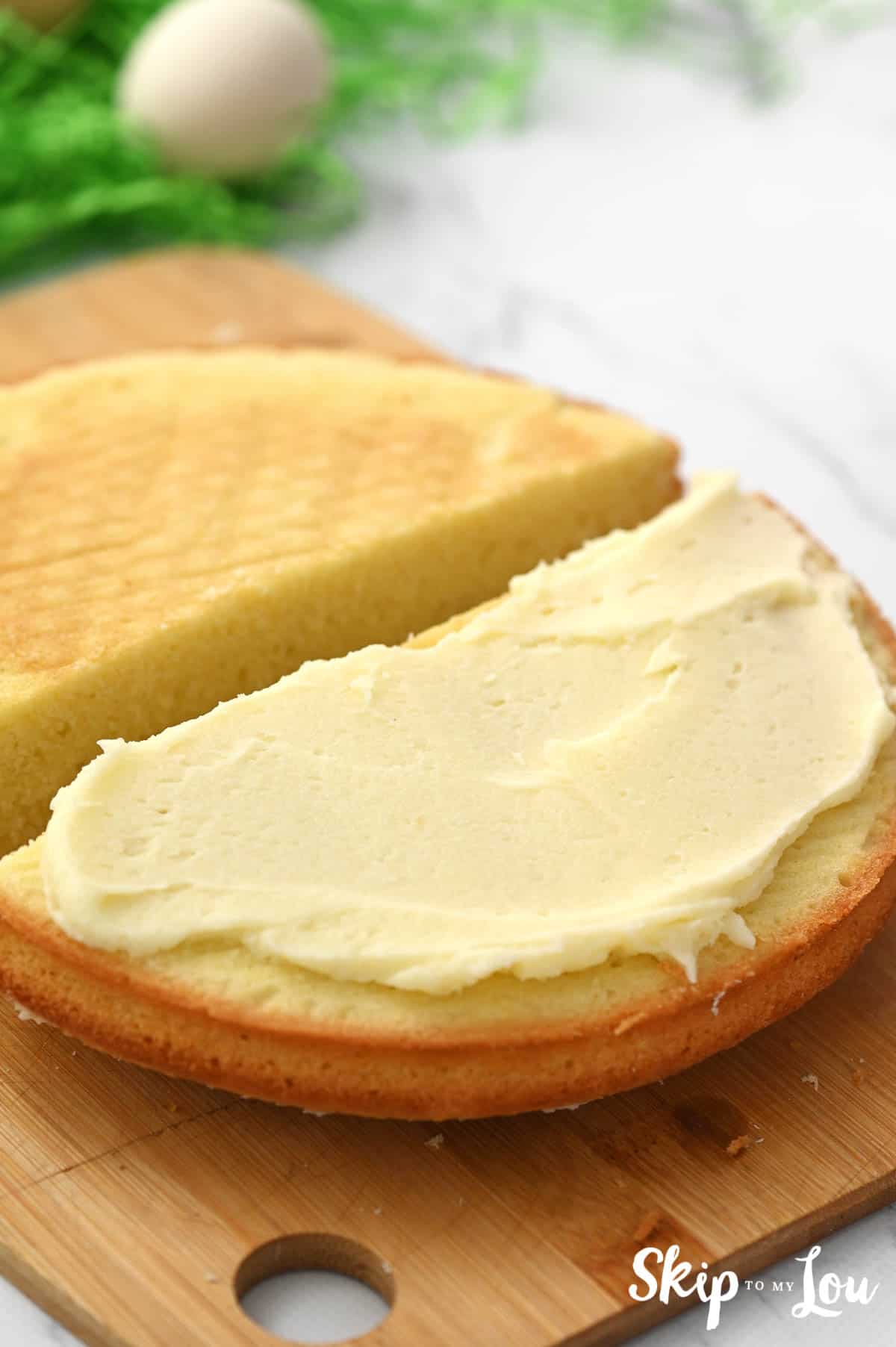 Frosting spread on one half of a round cake layer, by Skip to my Lou.