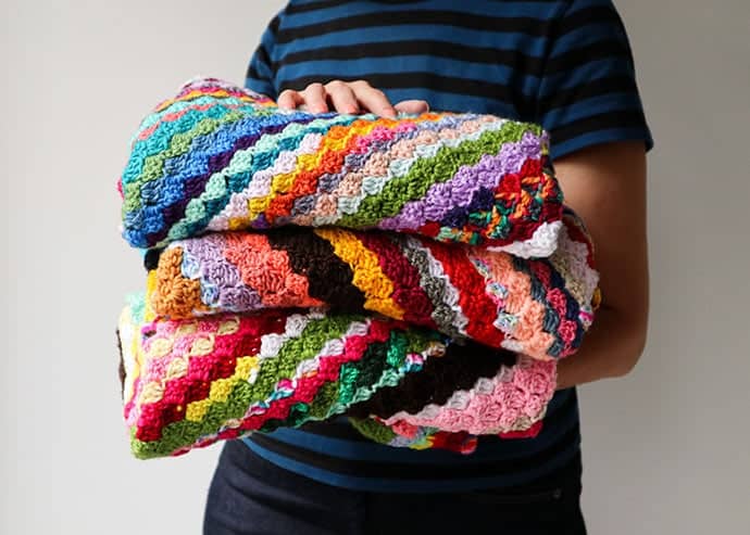 c2c crochet blankets folded with woman holding